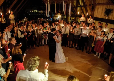 Ein Brautpaar tanzt in der Mitte eines Kreises aus Gästen mit Kerzen in einem festlich dekorierten Raum. Fotografiert von einem Hochzeitsfotografen in Moosach bei Grafing