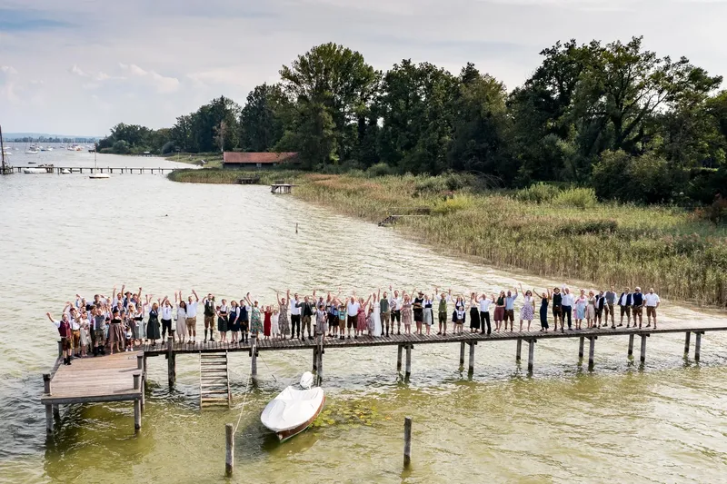 Luftaufnahme der Hochzeitsgesellschaft auf einem Steg am Ammersee bei Diessen