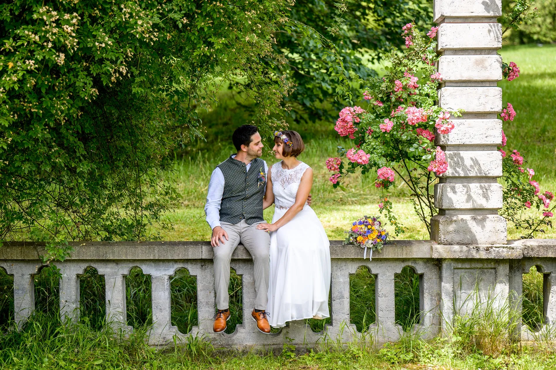 heiratsfotograf-diessen-ammersee Paar auf einer Mauer am Ammersee während des Brautpaar-Shootings